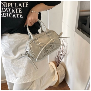 Détail du sac Boston gris clair avec nœud élégant et décoration à franges longues