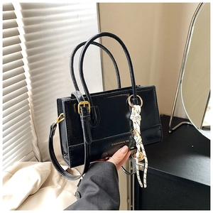 Detail der schwarzen glänzenden Handtasche mit goldenem Logo und Webanhänger