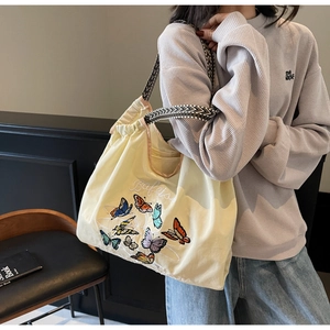 Détail du sac cabas en toile avec broderie papillon multicolore et bandoulière à motifs