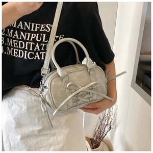 Détail du sac Boston gris-vert avec un nœud élégant et un design à sangles croisées