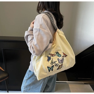 Détail du grand cabas en toile jaune clair avec motif papillon et bandoulières tissées