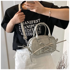 Détail d'un sac Boston gris stylé avec nœud papillon et bandoulière réglable