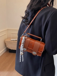 Brown leather pillow bag with embossed cartoon patterns and striped scarf on shoulder