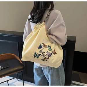 Détail du sac de shopping en toile avec broderies papillon et bandoulière tissée