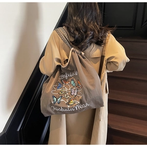 Détail de la broderie papillon et fermeture à cordon sur sac cabas en toile