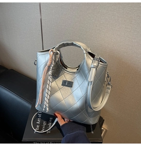 Gros plan d'un sac bandoulière argenté matelassé avec fermoir rotatif et poignée décorée