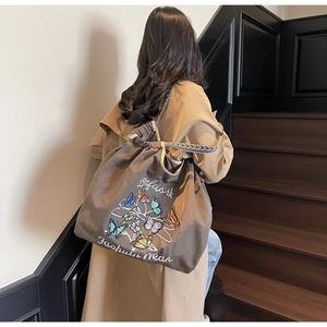 Vue détaillée du sac cabas en toile marron café avec broderie papillon et sangle