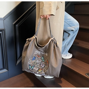 Détail d'un sac cabas en toile avec broderie papillon et anses en corde tressée