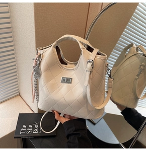 Détail d'un sac à main matelassé beige avec fermoir argenté et breloque de raquette