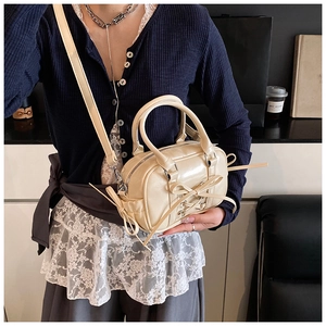 Détail du sac Boston beige brillant avec nœud et bandoulière amovible