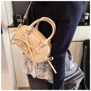 Sac Boston chic crème avec nœud papillon porté avec une tenue décontractée élégante