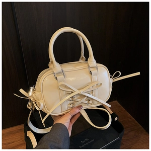 Détail du sac Boston crème avec décoration de nœud en cuir et finitions en métal argenté