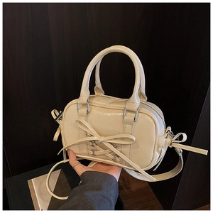 Détail du nœud papillon crème et des boucles en métal argenté sur le sac à main