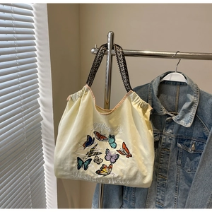 Détail de la broderie papillon colorée et des bretelles sur le sac cabas en toile