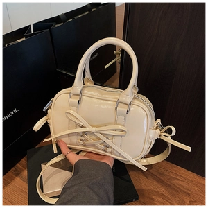 Détail du sac Boston beige avec texture brillante et nœud décoratif élégant