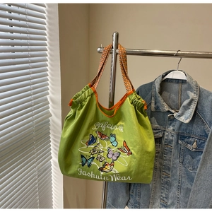 Détail du sac cabas en toile verte avec broderie papillon et anses tissées orange