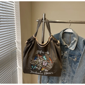 Détail de broderie papillon sur sac cabas en toile avec bandoulière tissée chic