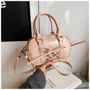 Détail du sac Boston rose avec nœud montrant la texture cuir et la bandoulière amovible
