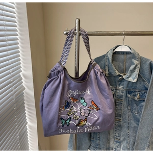 Détail du sac cabas en toile violette avec broderie papillon et bandoulière à motifs