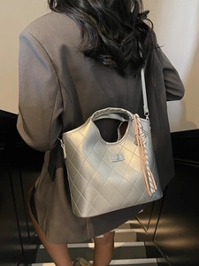 Sac fourre-tout argenté matelassé avec fermoir métal et pompons porté par un mannequin