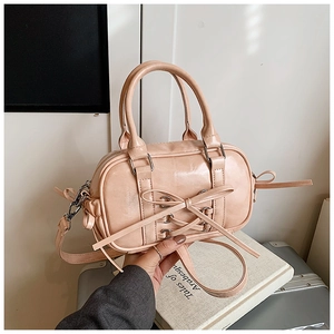 Détail du sac Boston en cuir verni rose avec nœud décoratif et boucles argentées