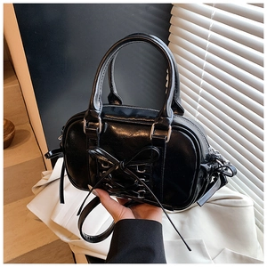 Détail du sac Boston noir avec nœud papillon, cuir verni et finitions métalliques argentées
