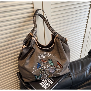 Détail de la broderie papillon sur un sac fourre-tout marron avec anse tissée