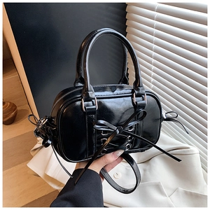 Détail d'un sac Boston noir brillant avec nœud papillon et texture de laçage