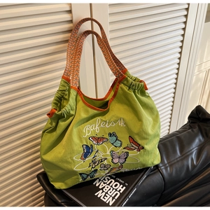 Détail du sac cabas vert avec broderie papillon et poignées à motifs orange