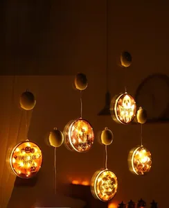 Close-up of warm yellow glowing Halloween LED hanging discs with pumpkin and ghost motifs