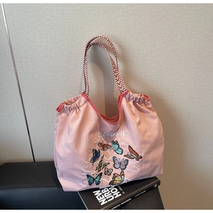 Détail du sac cabas en toile rose avec broderie papillon et fermeture à cordon rouge