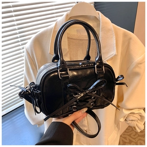 Détail du sac Boston en cuir verni noir avec un nœud élégant et des lacets croisés
