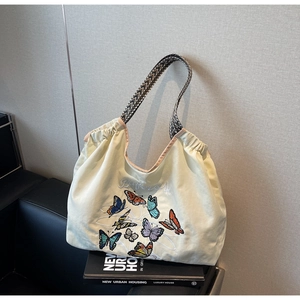Détail de broderie papillon colorée et poignée tissée sur sac cabas en toile