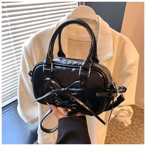 Détail du sac Boston noir avec nœud papillon en cuir PU brillant et finitions argentées
