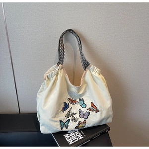 Détail du sac cabas en toile avec broderie papillon et bandoulière à motifs géométriques