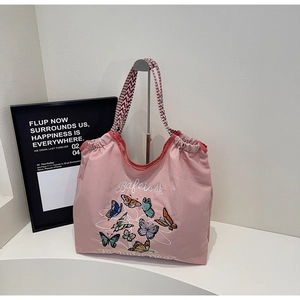 Détail du cabas rose avec broderie papillon et bandoulière tissée géométrique