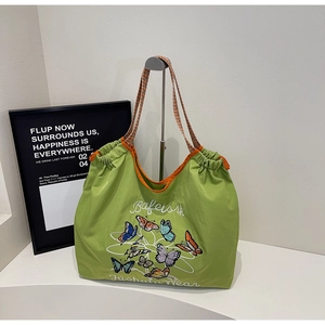 Détail du sac cabas vert en toile avec broderie papillon et bandoulière tissée rayée