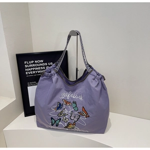 Détail du sac cabas en toile violette avec broderie papillon et sangle géométrique