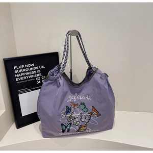 Détail du grand sac cabas violet avec broderies papillons et sangle à vagues bleues