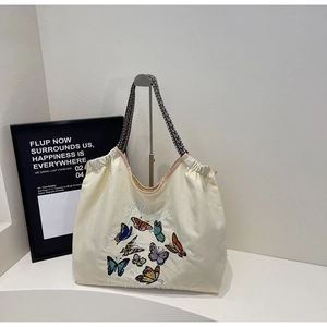 Détail du sac cabas en toile crème avec broderie papillon colorée et sangle tissée
