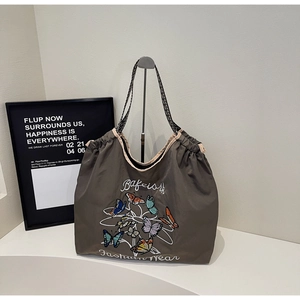 Détail du sac cabas marron foncé avec broderie papillon et bandoulières tissées