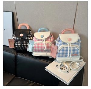 Mini plaid backpacks in various colors with leather flap and hanging card holders on a sofa