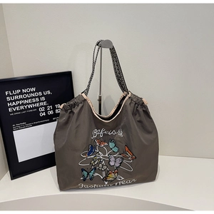 Détail de la broderie papillon colorée sur un grand sac cabas en nylon gris anthracite