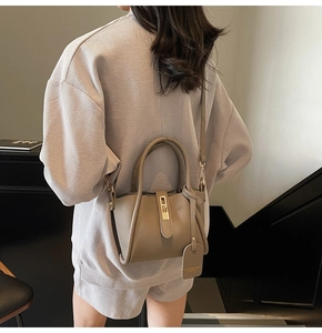 Detail of khaki leather bucket bag featuring a gold lock and adjustable shoulder strap