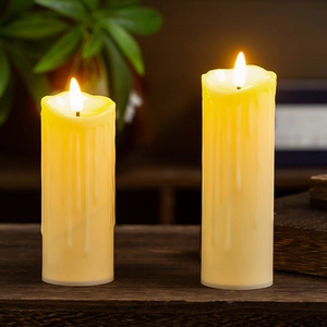 Macro shot of two dripping wax effect LED candles on vintage dark wood tabletop