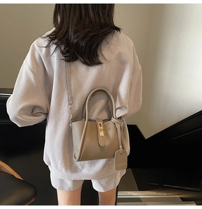 Back view of model carrying a grey litchi texture bucket bag on minimalist stairs