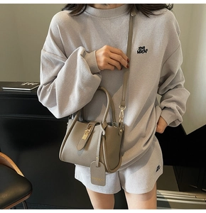 Detail of grey pebble leather bucket bag featuring a gold buckle and brand tag detail