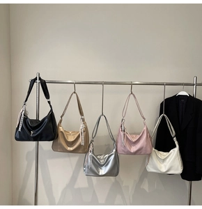 Five assorted colors of large Hobo shoulder bags hanging on a metal rack for display