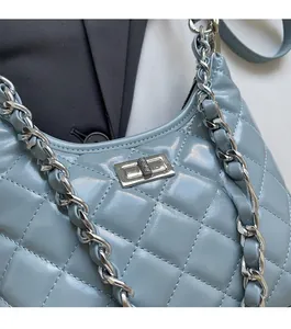 Detail of light blue quilted leather handbag featuring silver metal turn-lock and chain strap