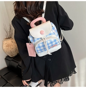 Detailed view of mini checkered backpack with pink handle and matching card holder pouch